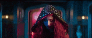 a woman with long red hair is standing in a dark room looking at the camera .