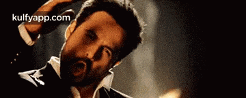 a man in a tuxedo is scratching his head while looking at the camera .