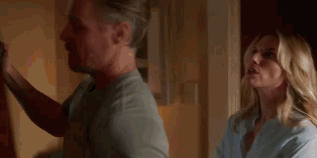 a woman is holding a piece of paper in front of a man in a room .