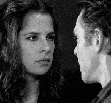 a black and white photo of a man and woman looking at each other .
