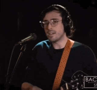 a man wearing headphones is singing into a microphone and playing a guitar