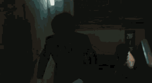 a man in a white shirt is standing in a dark room with a light shining through the window .