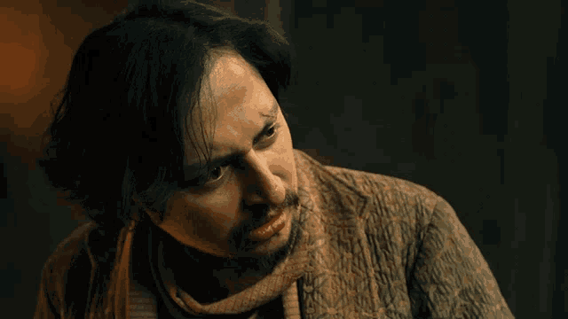 a man with a scarf around his neck looks to his left