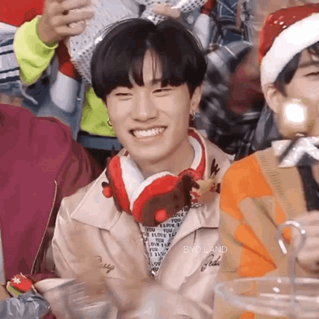 a young man wearing a santa hat and headphones smiles for the camera .