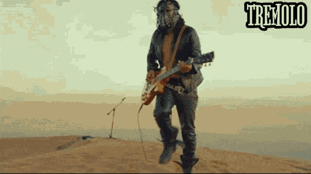 a man playing a guitar in the desert with the word tremolo behind him