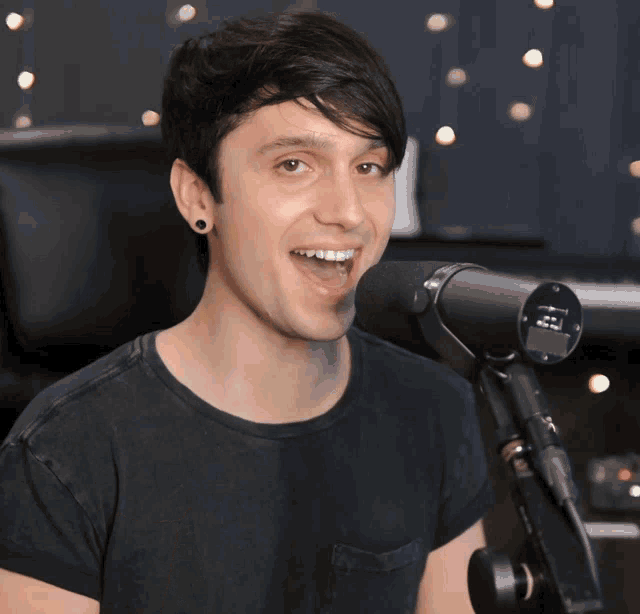a man in a black shirt is smiling in front of a microphone that says yamaha on it