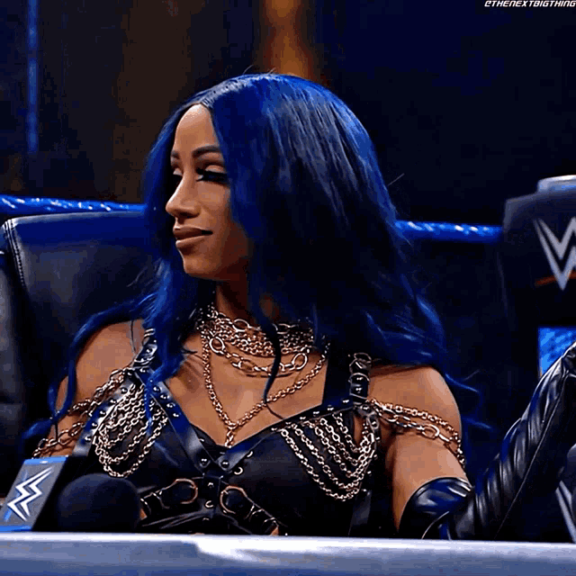 a woman with blue hair is sitting in front of a microphone