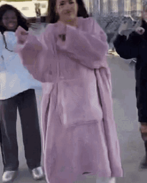 a woman in a pink coat is dancing with another woman .