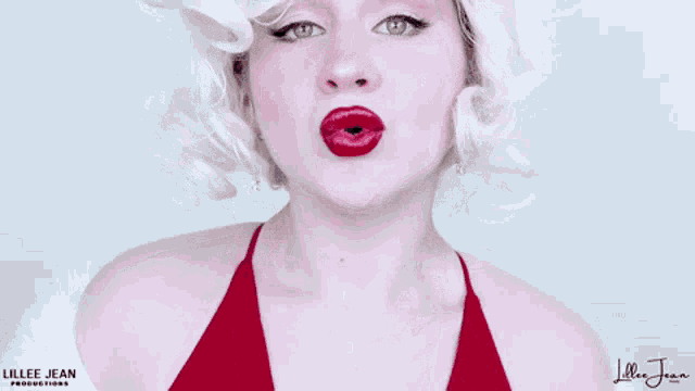 a woman with blonde hair and red lipstick is smiling with her mouth open .