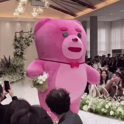 a pink teddy bear is walking down a runway at a wedding