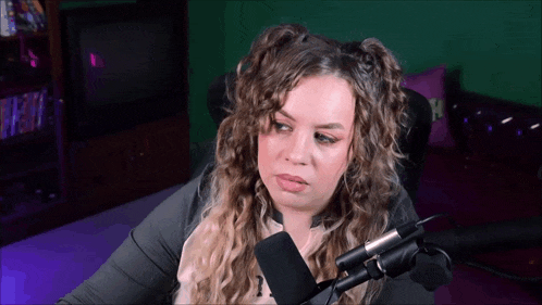 a woman is sitting in front of a microphone with a purple background