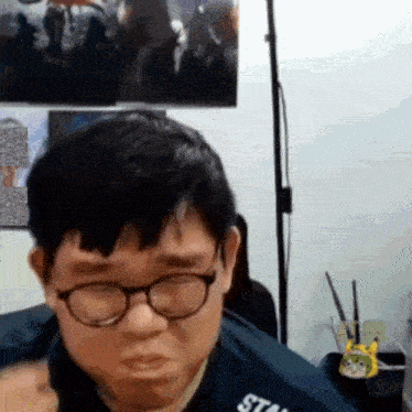 a man wearing glasses and a blue shirt that says stan