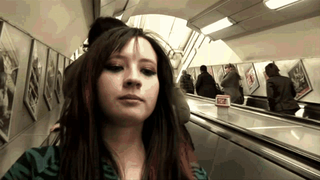 a woman riding an escalator with a sign that says stop