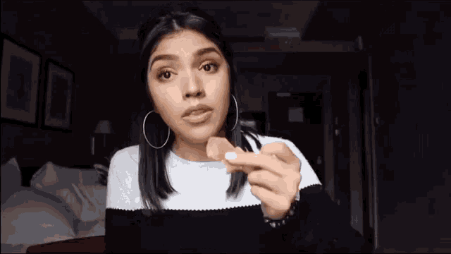 a woman with hoop earrings is holding a piece of food
