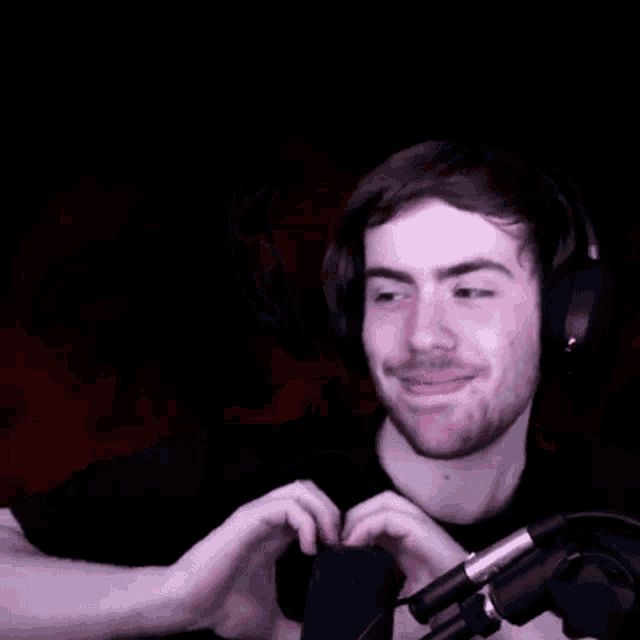 a man in headphones is making a heart shape with his hands .