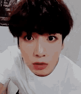 a close up of a person 's face with a white t-shirt on making a funny face .