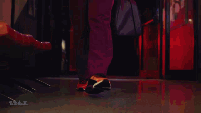 a woman in a purple jumpsuit is walking down a hallway in front of a neon arrow sign