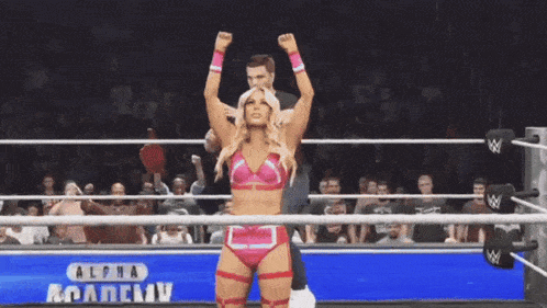 a woman is standing in a wrestling ring with her arms in the air and the words alpha academy behind her