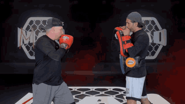two men in boxing gloves are standing in front of a sign that says mma