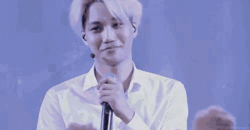 a man in a white shirt is holding a microphone and making a face .