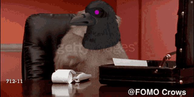 a cat with a crow on its head sits at a desk in front of a briefcase
