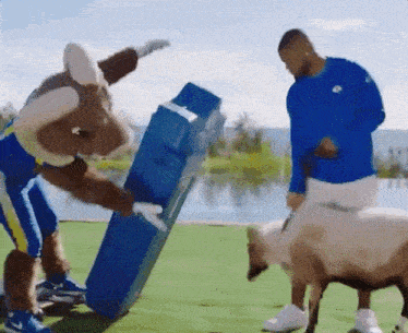 a man in a blue shirt is standing next to a mascot holding a blue box