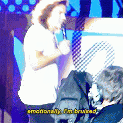 a man singing into a microphone with the words " emotionally i 'm bruised " above him