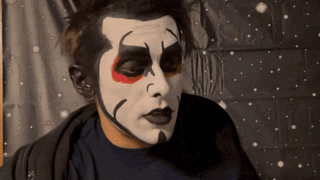 a man with his face painted like a clown looks at the camera
