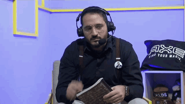 a man wearing headphones is reading a book next to a black bag that says axe