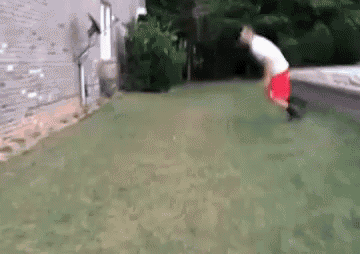 a man in red shorts is jumping over a fence in a yard .
