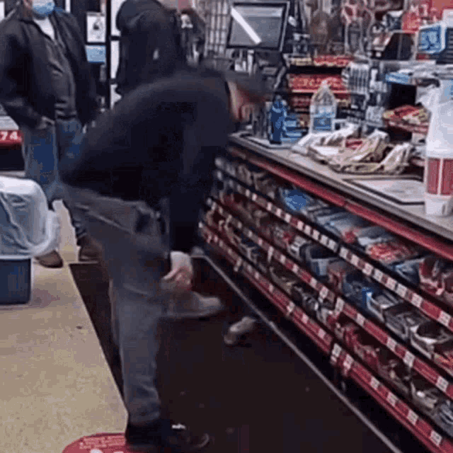 a man is standing in a convenience store looking at a bottle of water .