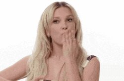 the woman is blowing a kiss with her hand .