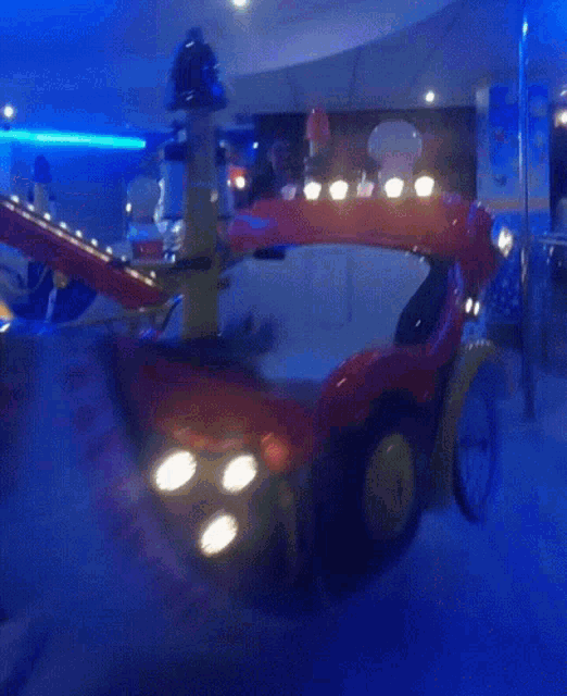 a red car with a yellow fender is in a dark room with purple lights