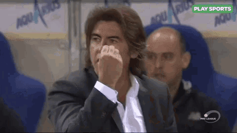 a man in a suit is covering his nose while watching a soccer game sponsored by play sports