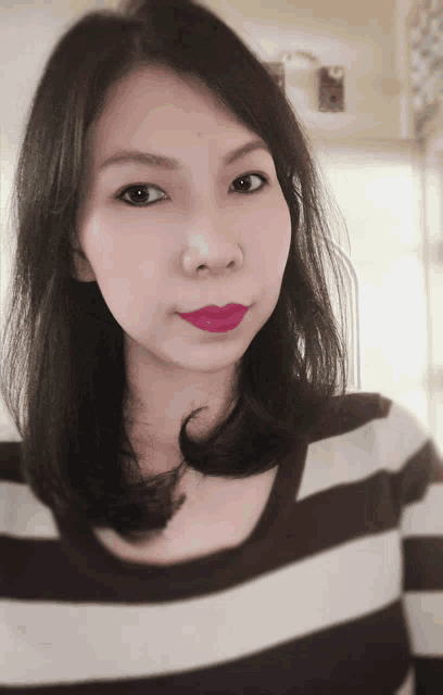 a woman wearing a black and white striped shirt has a red lip