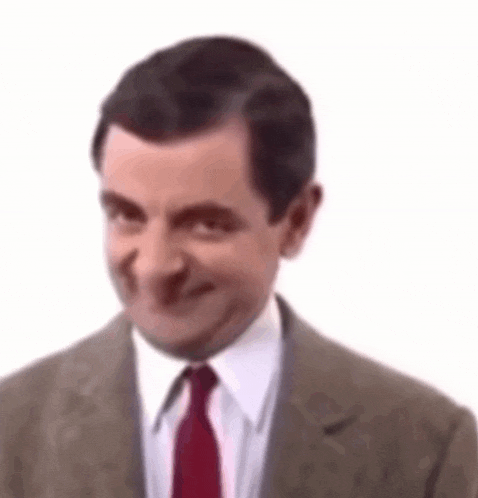 mr bean is wearing a suit and tie and is making a funny face .