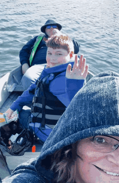a boy wearing a life jacket is waving his hand