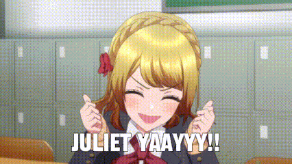 a girl in a school uniform is making a heart with her hands in a classroom and says juliet yaayyy !