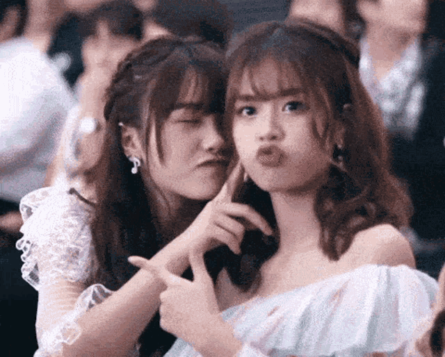 two young women are making funny faces while sitting next to each other .
