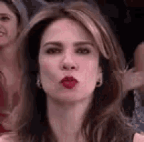 a close up of a woman blowing a kiss with red lips .