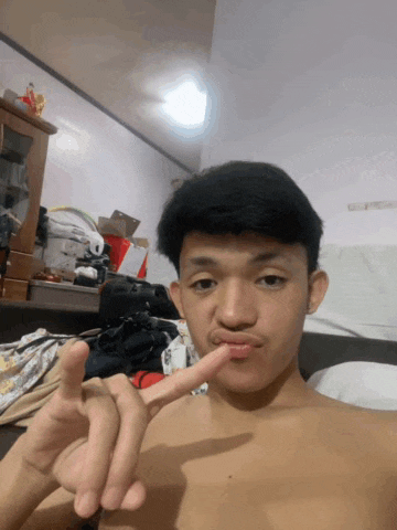 a young man without a shirt is making a heart shape with his finger