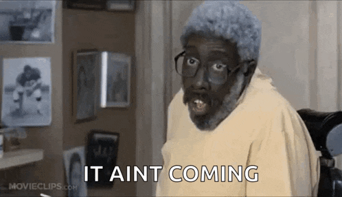 a man with glasses and a beard is sitting in a chair and saying `` it aint coming '' .