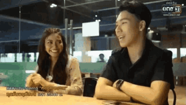 a man and a woman are sitting at a table in front of a one 37 sign