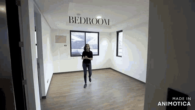 a woman is walking through an empty bedroom with the word bedroom on the wall above her
