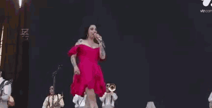 a woman in a pink dress is dancing on stage with a microphone .