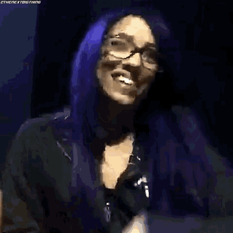 a woman with purple hair and glasses is making a funny face and saying `` i 'm famous '' .