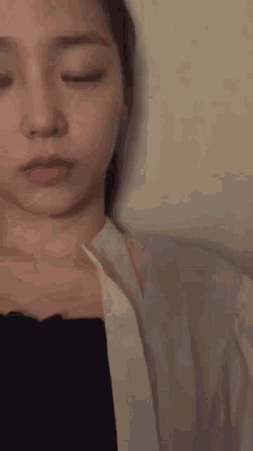 a woman with her eyes closed is wearing a black top and a white shirt .