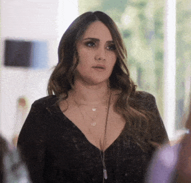 a woman wearing a black top and a necklace with a pendant that says ' u ' on it