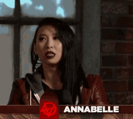 a woman in a red jacket stands in front of a banner that says annabelle