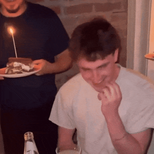 a man holding a plate of food with a lit candle